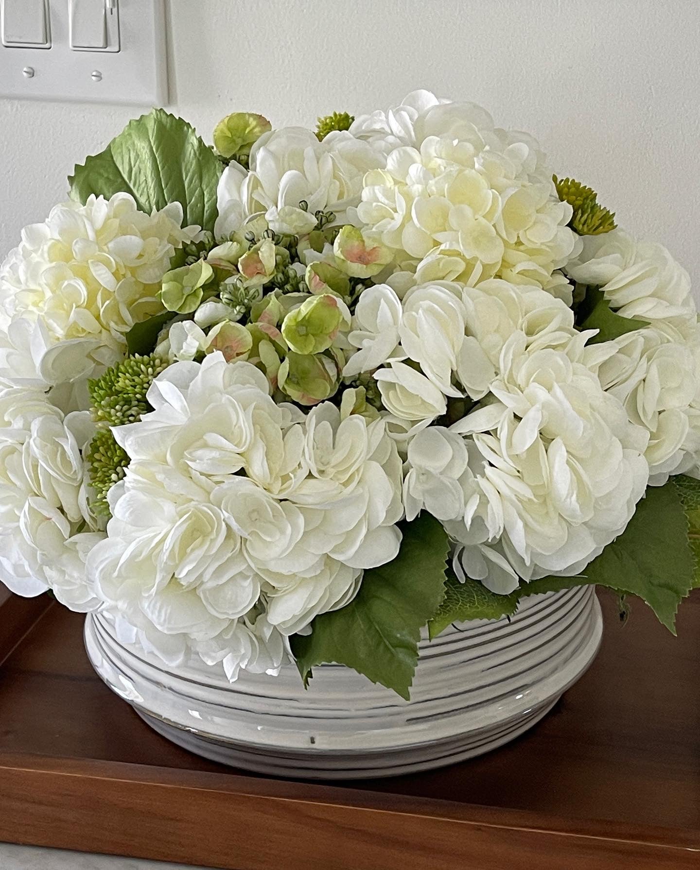 White hydrangea arrangement in a ceramic container.