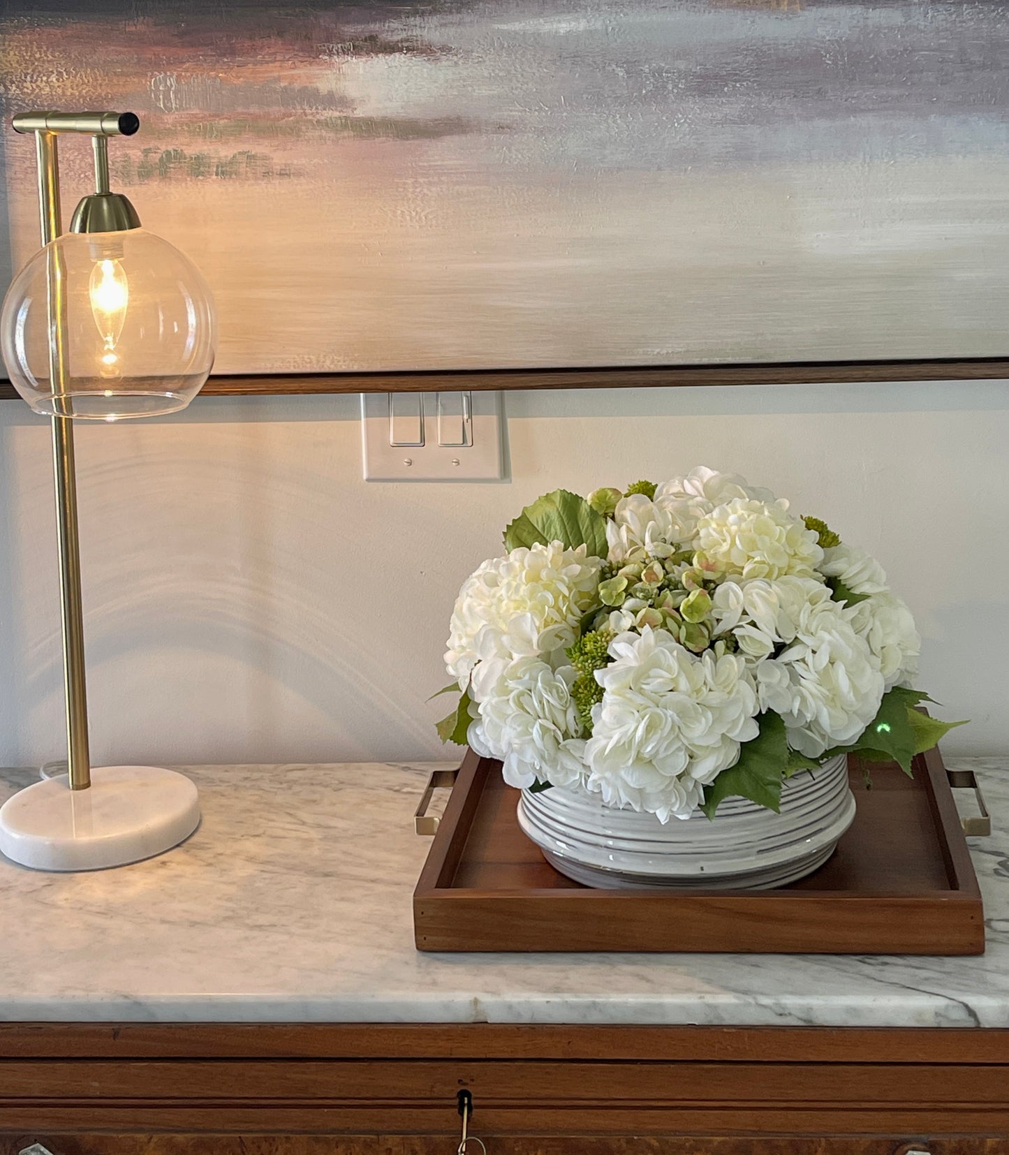 Closeup of white hydrangea arrangement in a ceramic container.