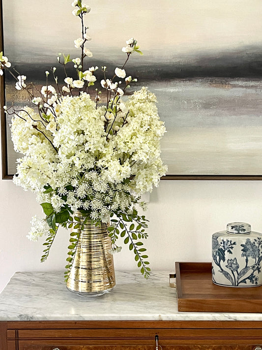 Arrangement of white blooms in gold vase